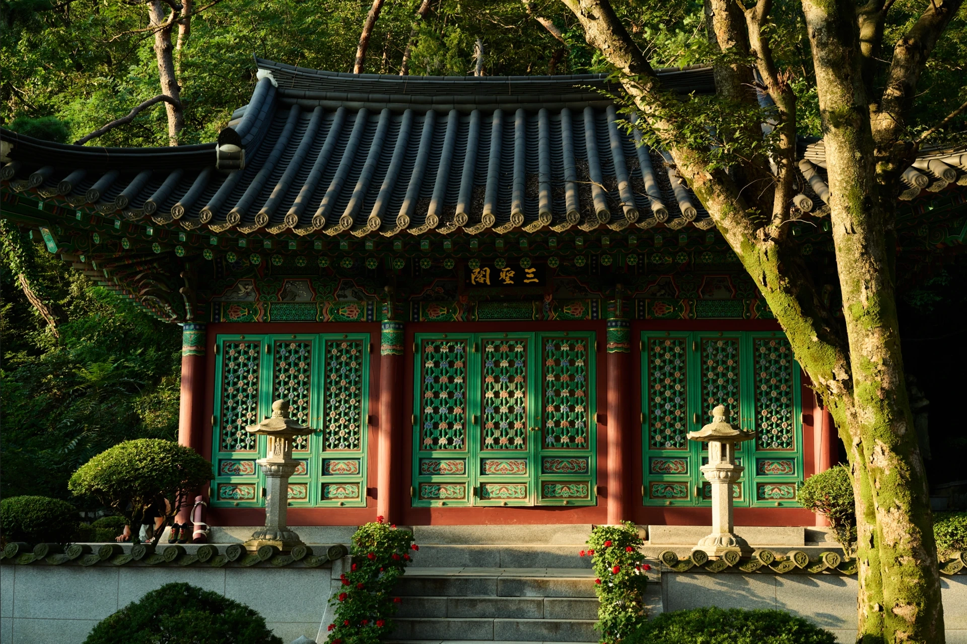 Green temple doors and sunlit stone lanterns