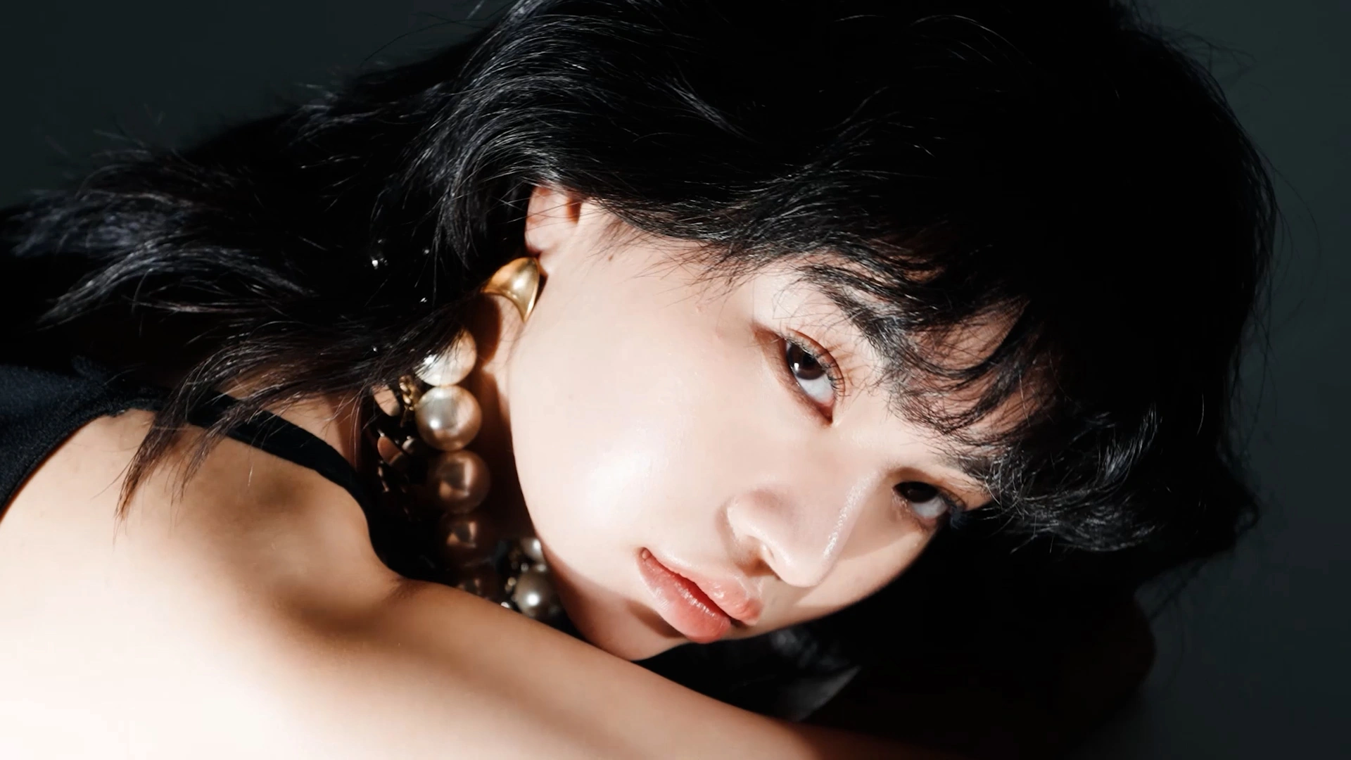 A dark-haired portrait against deep shadow