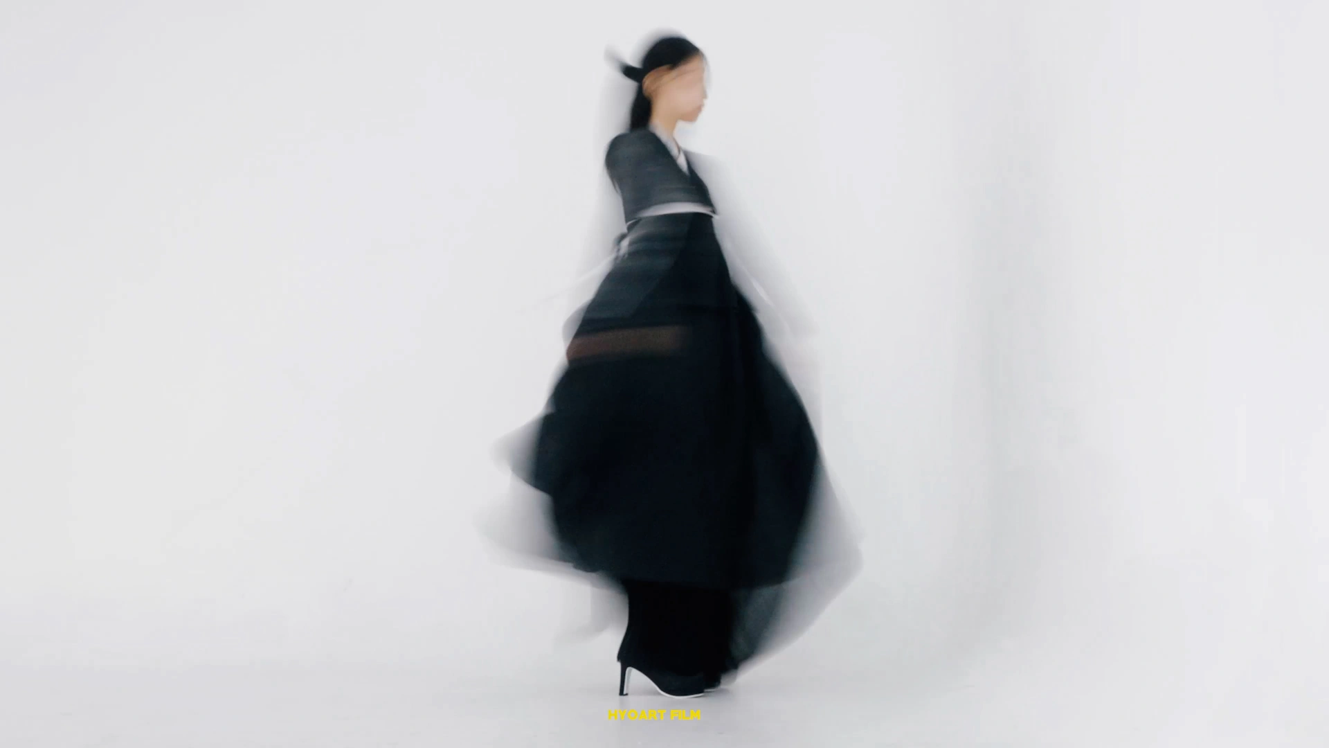 A dark silhouette moving across a white studio