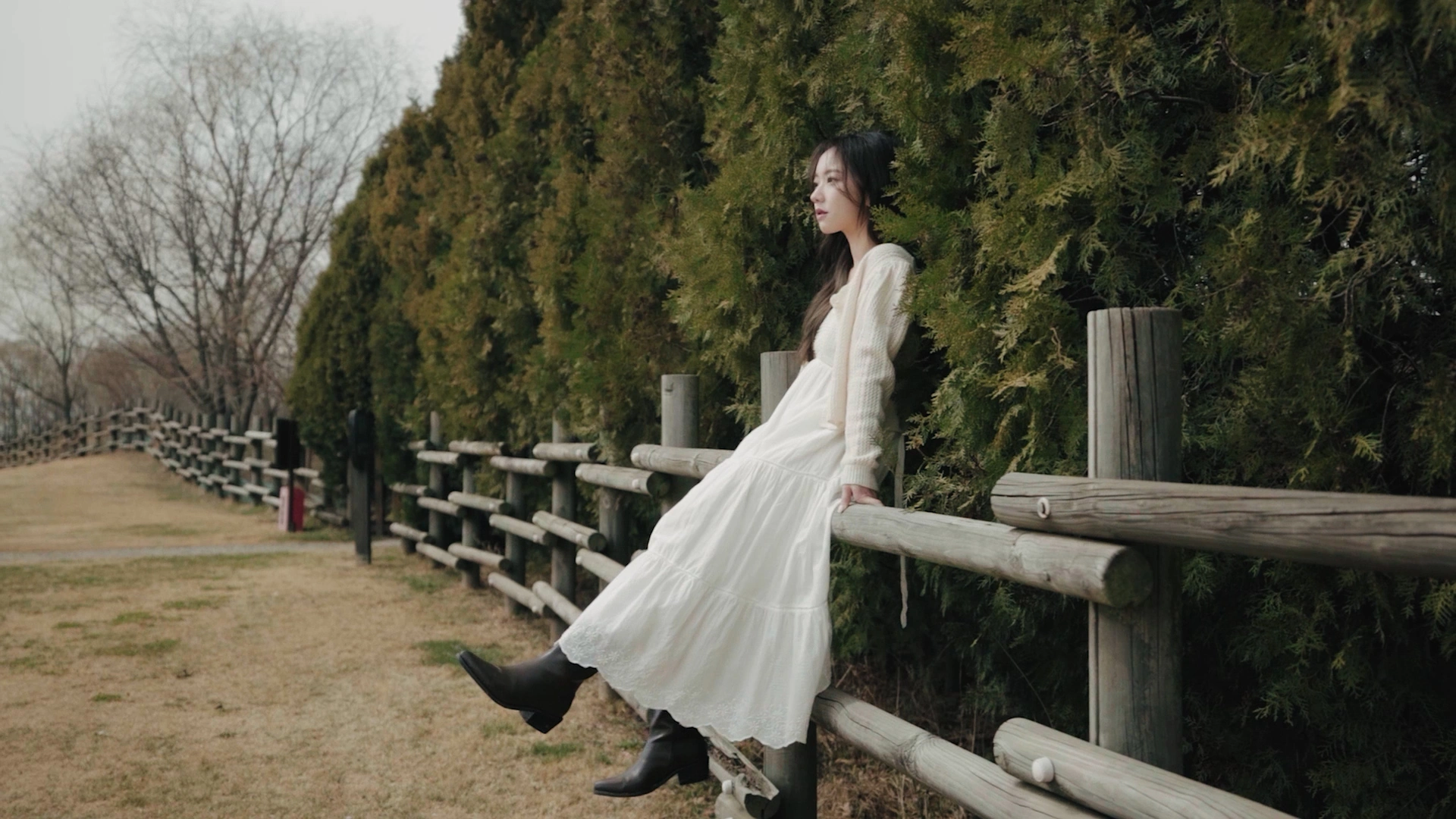 A white dress beside a wooden fence and trees